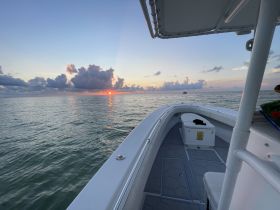 A serene view from the bow of a boat at sunset, showcasing calm waters and a beautiful sky — perfect for evening cruises.
