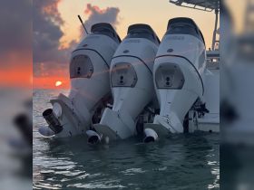 A striking view of three powerful outboard motors silhouetted against a vibrant sunset, showcasing the beauty of boating at dusk.