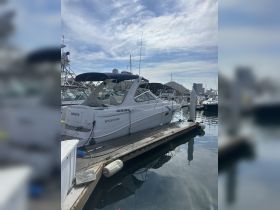 A sleek yacht named 'Coqueto' docked at Cabo San Lucas, showcasing its elegant design against a picturesque marina backdrop.