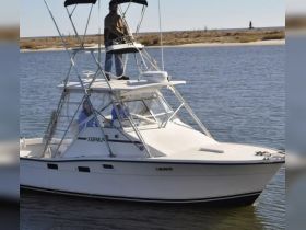 A fishing boat named 'TOPAZ' with crew members onboard navigating through calm waters, showcasing the excitement of a day on the water.