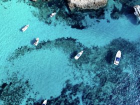 Aerial view of several boats navigating through crystal-clear turquoise waters, showcasing the beauty of the marine landscape.