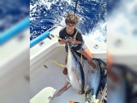 A young boy proudly holds his catch while fishing on a boat, showcasing the excitement of a successful fishing trip.