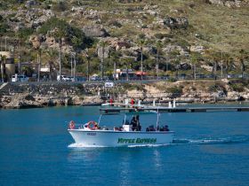 The Yippee Express boat cruises through clear waters, showcasing a lively group of passengers enjoying their day on the water.