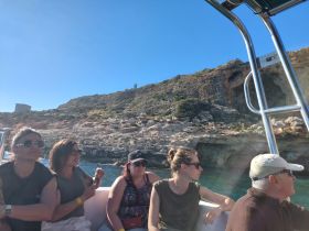 A group of friends enjoys a scenic boat ride, taking in the stunning coastal views — perfect for adventure seekers and nature lovers.