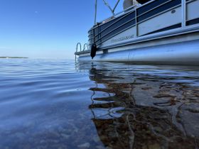 A serene view of a pontoon boat gliding over calm waters, showcasing the tranquil beauty of a day on the lake.