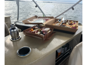 A beautifully arranged charcuterie board and cocktail shaker set up on a boat's countertop, perfect for enjoying snacks while cruising on the water.