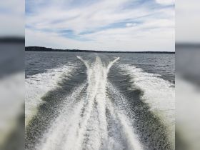 A stunning view of boat wake trailing behind as the vessel navigates through open waters, showcasing the beauty of a day on the lake.