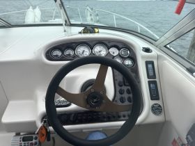 A detailed view of the helm and console of a boat, showcasing the steering wheel and various gauges, ideal for navigation and control.