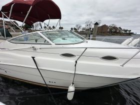 A sleek speedboat docked at the marina, showcasing its elegant design and features, with two people visible nearby.