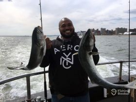 A happy angler proudly displays his impressive catch while fishing on a boat, showcasing the thrill of a successful day on the water.