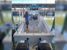 A man stands at the helm of a well-equipped fishing boat, showcasing the interior layout and console — perfect for fishing enthusiasts.