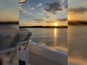 A serene sunset view from the deck of a boat, showcasing the tranquil waters and vibrant sky — perfect for evening cruises.