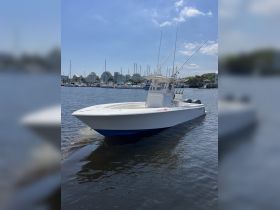 A sleek speedboat navigates the calm waters, showcasing its impressive design against a backdrop of a marina.