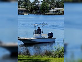 A man navigates a small boat on calm waters, showcasing a perfect day for fishing or leisure on the water.