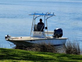 A man operates a small boat on calm waters, showcasing a serene fishing experience in nature.