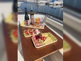 A beautifully arranged charcuterie spread featuring fruits, meats, and drinks, perfect for enjoying onboard a boat. Ideal for entertaining guests during a relaxing day on the water.