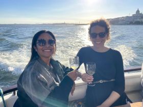 Two friends enjoy cocktails while cruising on a boat, capturing the essence of a perfect sunset cruise experience.