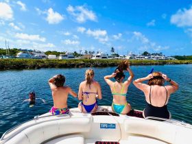 A group of friends enjoys a sunny day on the water, preparing for a snorkeling adventure while a swimmer splashes nearby — perfect for summer fun and aquatic exploration.