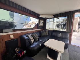 Cozy interior of a boat featuring a comfortable lounge area with plush seating and a stylish table, perfect for relaxing while on the water.