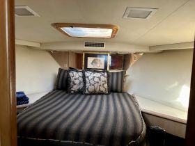 Cozy cabin interior featuring a comfortable bed adorned with decorative pillows, perfect for relaxation on a boat getaway.