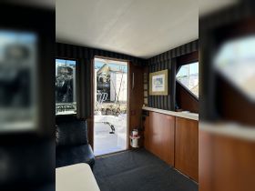 Interior view of a boat cabin featuring a cozy seating area and access to the deck, perfect for relaxing while enjoying the marine environment.