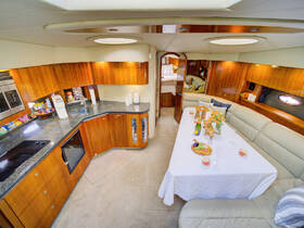 A beautifully designed boat interior featuring a spacious dining area and modern kitchen amenities, perfect for entertaining guests while cruising.