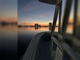 A serene sunset view from the deck of a boat, showcasing the calm waters and city skyline in the background — perfect for evening cruises.