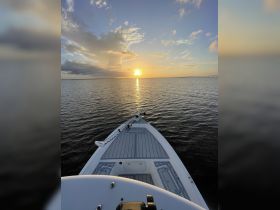 A serene view from the front of a boat at sunset, showcasing the calm waters and beautiful sky — perfect for peaceful evening cruises.