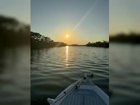 A serene sunset view from the bow of a boat, reflecting golden hues on the water — perfect for peaceful evening cruises.