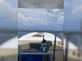 View of the helm and console inside a boat, showcasing essential navigation equipment and a clear perspective of the open water ahead.