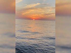 A stunning sunset over calm ocean waters, creating a picturesque backdrop perfect for evening boat cruises.