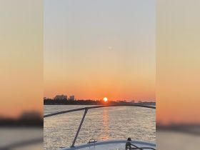 A stunning sunset viewed from the bow of a boat, reflecting on the water — an ideal scene for evening cruises and relaxation on the water.