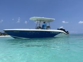 A sleek speedboat named 'LAVENIER' glides through crystal-clear waters, showcasing its vibrant design against a stunning tropical backdrop.