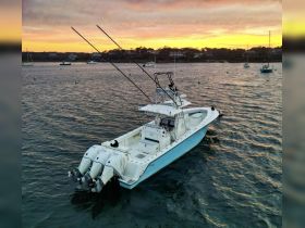 A stunning aerial view of a sleek speedboat cruising through calm waters at sunset, showcasing its powerful engines and design — perfect for fishing or leisure outings.