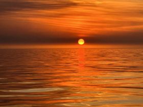A breathtaking sunset over calm ocean waters, creating a stunning reflection that captures the beauty of nature — perfect for romantic evenings or serene boat trips.