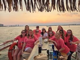 A lively group of friends celebrates at sunset aboard a boat, showcasing the perfect atmosphere for memorable gatherings and parties on the water.