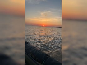 A serene sunset view over the water, with a portion of a boat visible in the foreground — perfect for capturing the tranquility of evening boat rides.