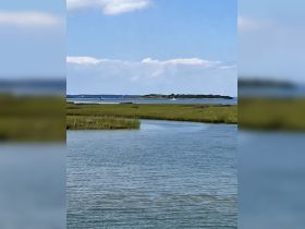 A serene view of a coastline with an island in the distance, showcasing the beauty of nature and tranquil waters — perfect for exploring by boat.