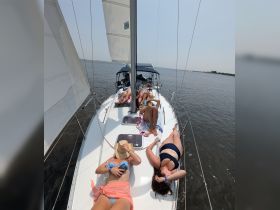A group of friends relaxes on the deck of a sailboat, enjoying the sun and the serene waters — perfect for a day of sailing and leisure.