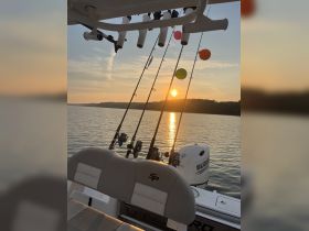 A serene view of fishing rods set up on a boat, with a stunning sunset reflecting on the water — perfect for a peaceful day of fishing.