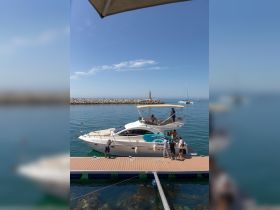 A lively group gathers on the dock beside a yacht, enjoying a sunny day on the water — perfect for social gatherings and celebrations.