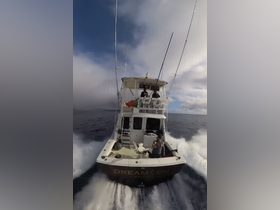 A fishing boat named 'DREAM ON' speeds through the water, showcasing the thrill of a day on the ocean with crew members actively engaged.