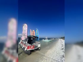 A colorful tiki boat docked on a sandy beach, showcasing vibrant signage for shaved ice, perfect for a fun day on the water.
