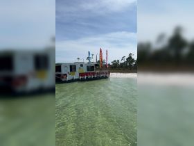 A floating boat is anchored in shallow waters, with a person enjoying the beachside scenery — perfect for water activities and relaxation.