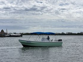 A center console boat navigates through calm waters, showcasing its sleek design and fishing gear, perfect for a day out on the water.