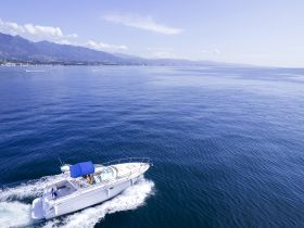 Aerial view of a sleek speedboat cruising through calm waters, showcasing the stunning coastal scenery in the background — perfect for adventure seekers and day trips on the water.