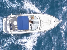 Aerial view of a sleek boat cruising through vibrant blue waters, showcasing its elegant design and spacious deck — perfect for leisurely outings on the water.