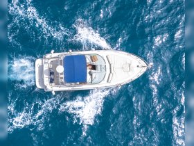 Aerial view of a sleek yacht cruising through vibrant blue waters, showcasing its elegant design and inviting deck space.
