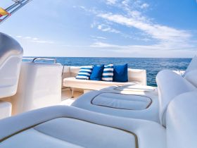 A bright and inviting interior view of a boat's seating area, featuring comfortable cushions and a stunning ocean backdrop, perfect for relaxation on the water.