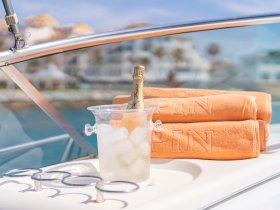 A stylish setup featuring a chilled bottle of champagne in an ice bucket alongside plush towels, perfect for a luxurious day on the water.